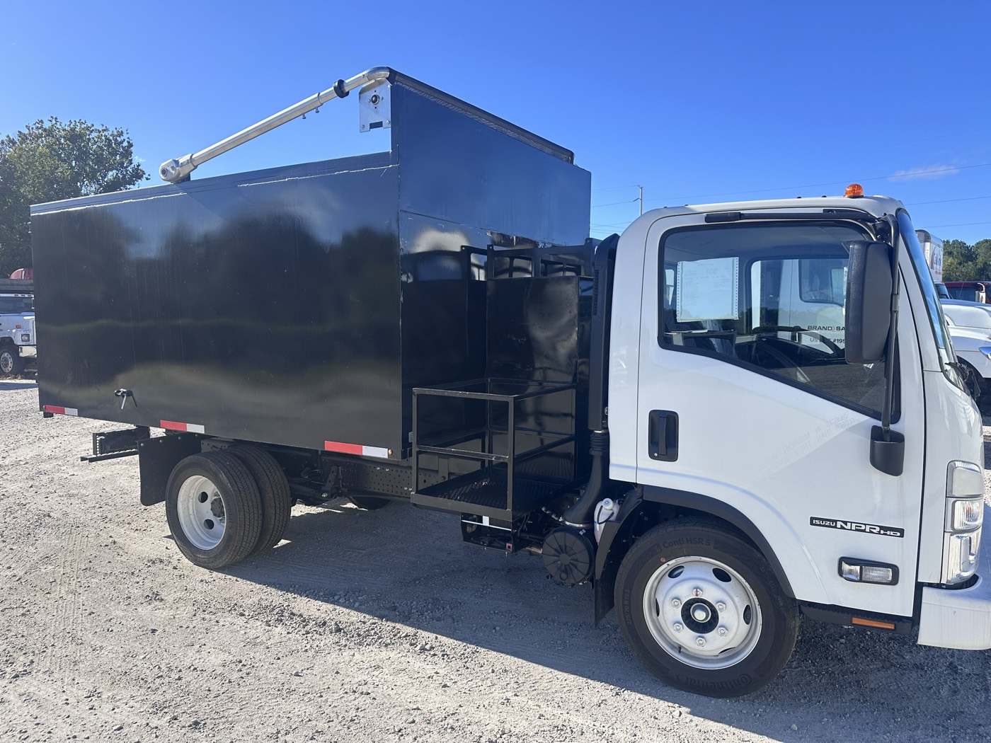 Passenger side of the 2026 Isuzu NPR HD with a black STB junk removal body
